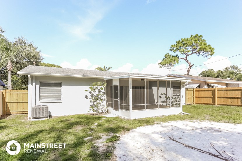 a small white house with a yard and a fence