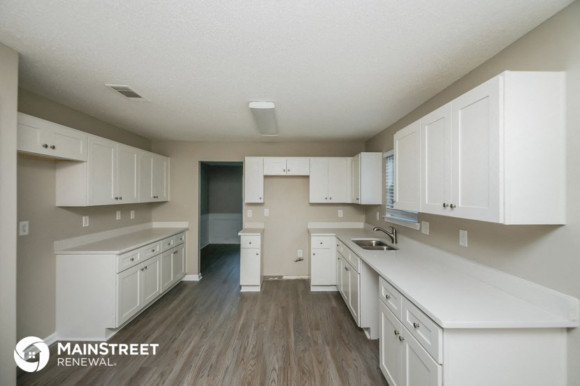 a large white kitchen with white cabinets and wood flooring