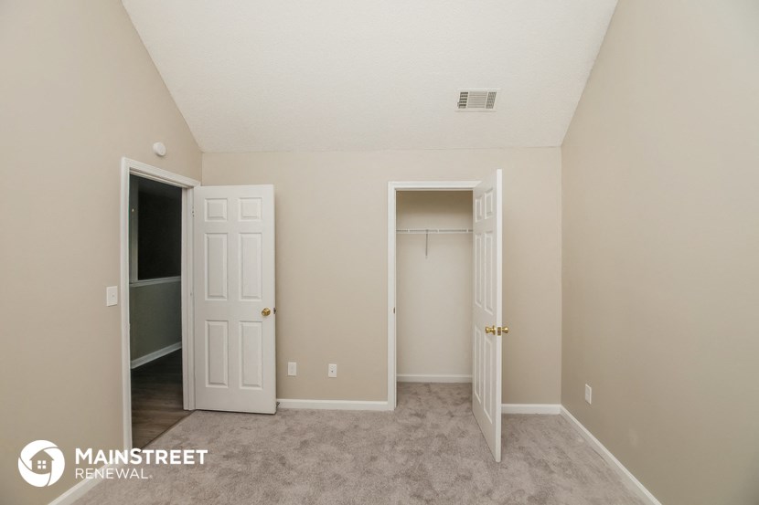 a bedroom with two doors and a closet and a carpeted floor