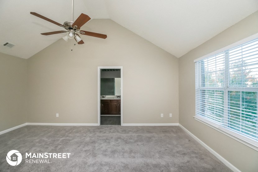 an empty living room with a ceiling fan and a large window