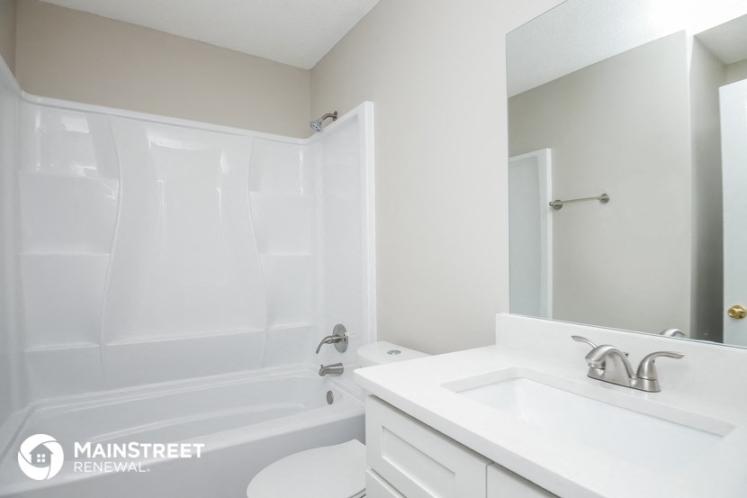 a white bathroom with a tub and a sink and a mirror