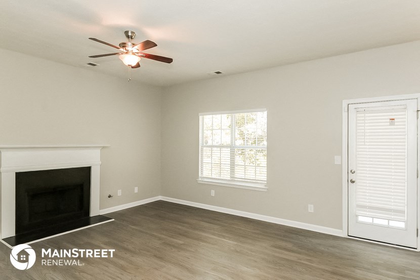 a living room with a fireplace and a ceiling fan