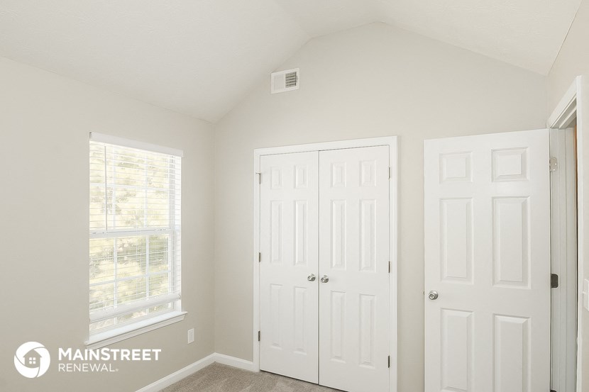 a bedroom with two white doors and a window