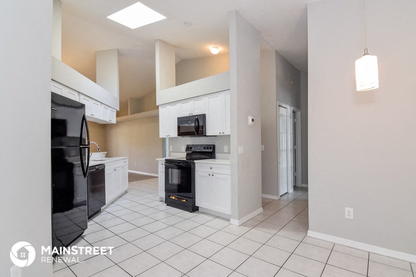 a kitchen with white cabinets and black appliances and a white tile floor