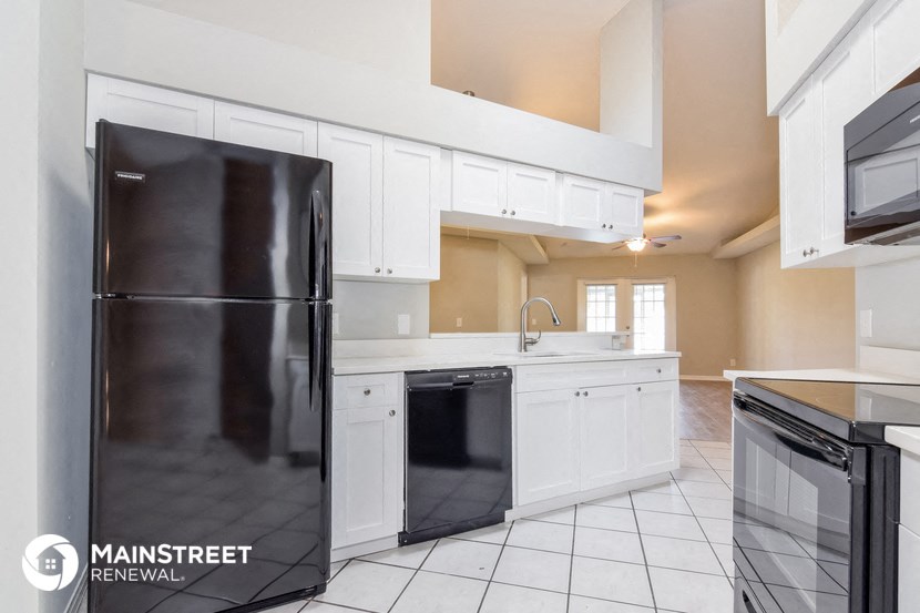 a kitchen with white cabinets and a black refrigerator
