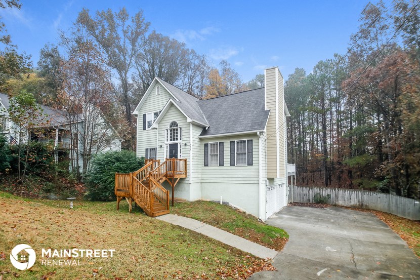 the front of a white house with a driveway and a deck