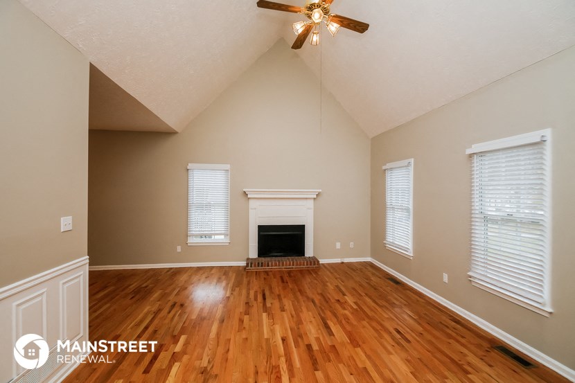 the living room with wood floors and a fireplace