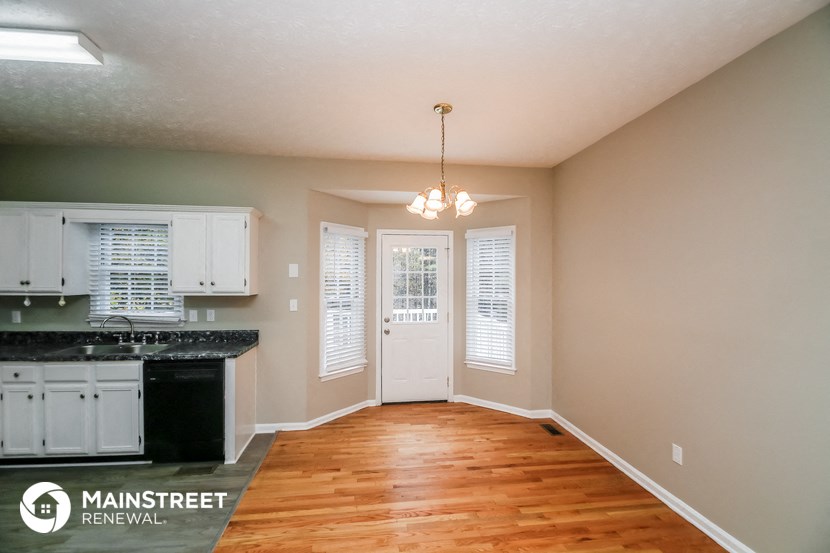an empty kitchen with a hard wood floor and white cabinets