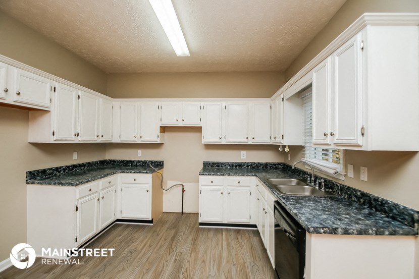 a kitchen with white cabinets and granite counter tops and a sink