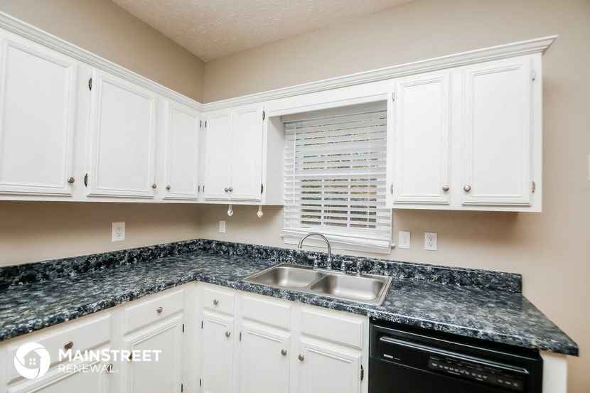 a kitchen with white cabinets and granite counter tops and a sink