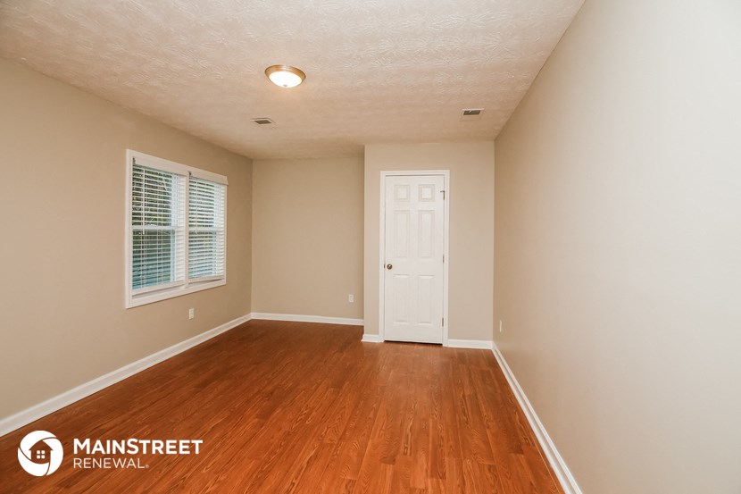 the spacious living room with hardwood flooring and a white door