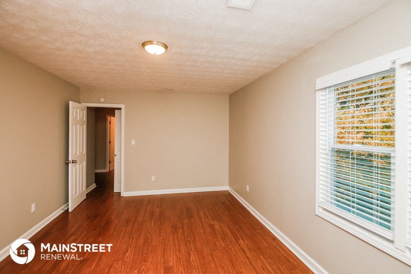 a spacious living room with wood flooring and a large window