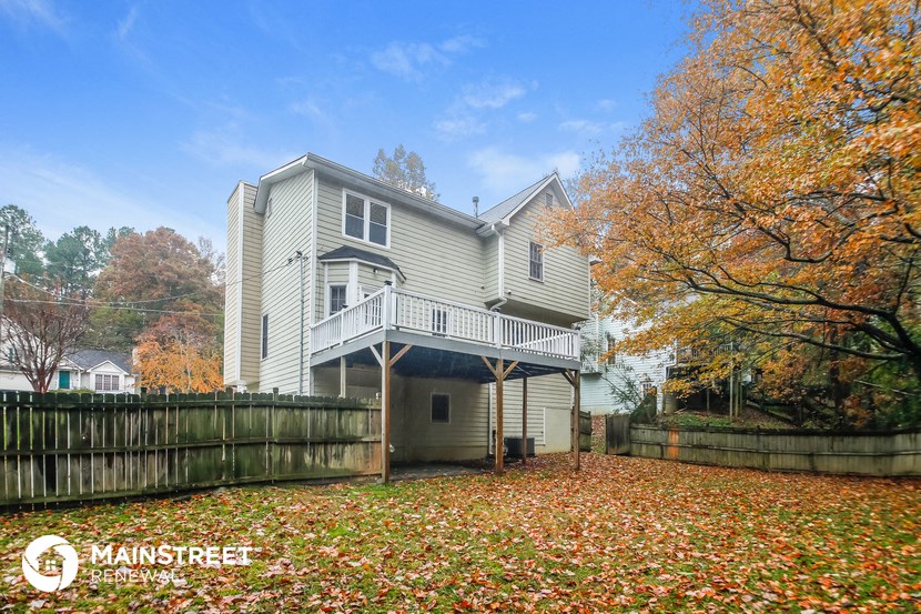 the back of a house with a yard covered in fallen leaves