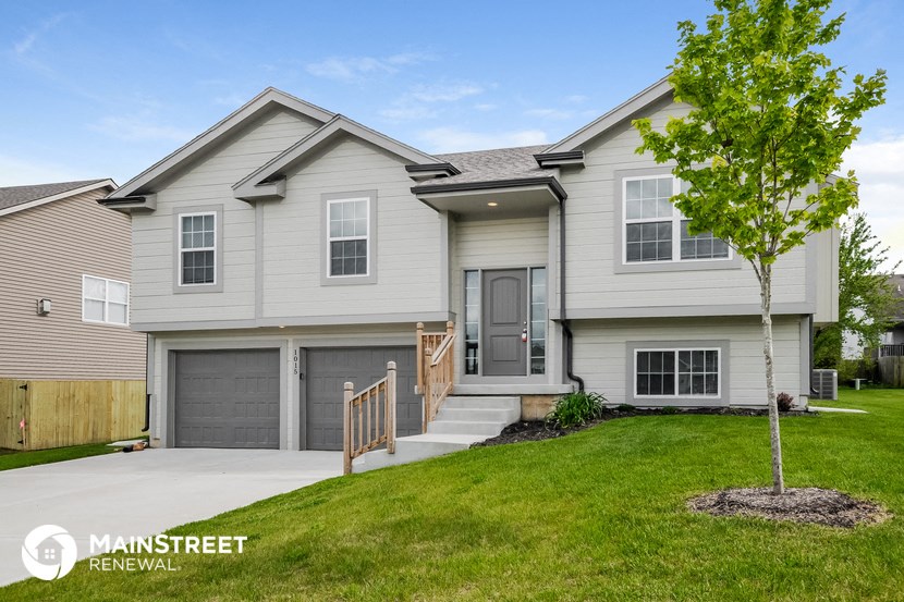 a white house with two garage doors and a driveway