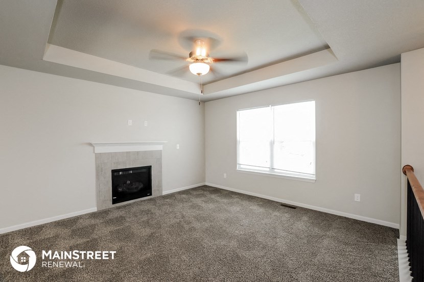 the living room with fireplace and ceiling fan