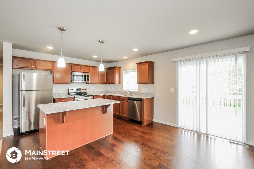 a kitchen with wooden cabinets and stainless steel appliances and a large window