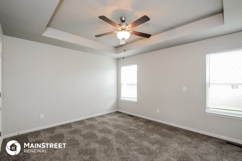 the spacious living room with ceiling fan and carpet