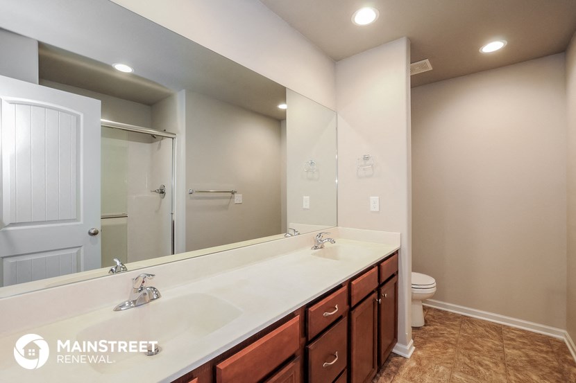 the master bathroom has a large vanity mirror and a toilet