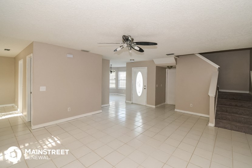 an empty living room with a ceiling fan and a tiled floor