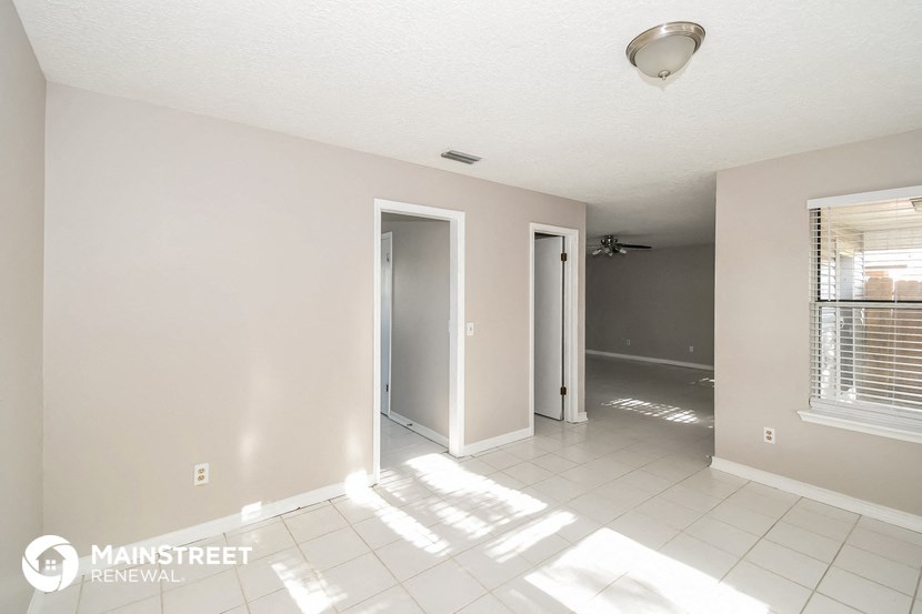 the living room and hallway of an empty house with the door open
