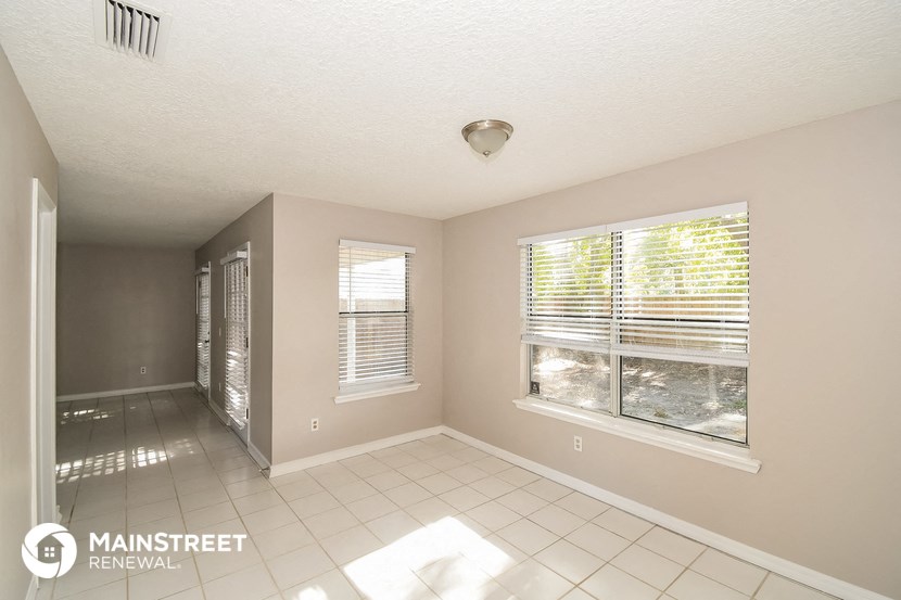 an empty living room with two windows and a tiled floor
