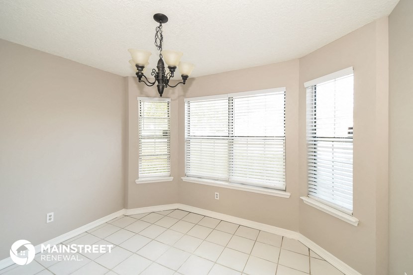 a dining room with a chandelier and three windows