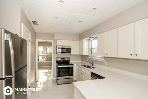 a white kitchen with stainless steel appliances and white cabinets