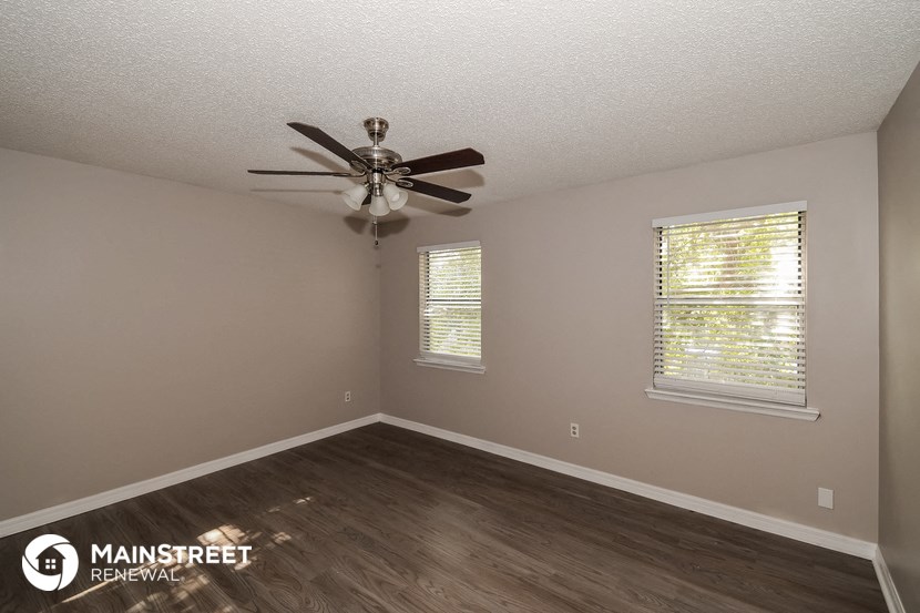 the interior of a bedroom with a ceiling fan and window