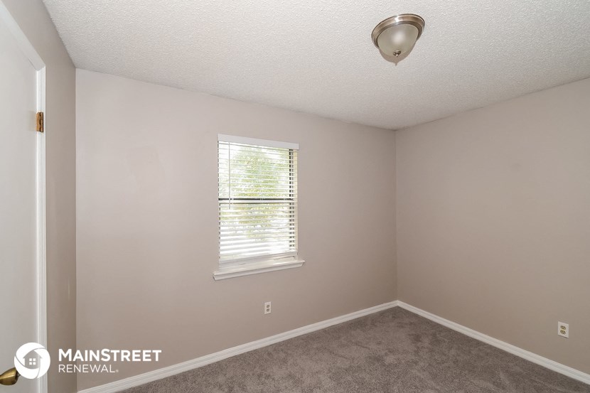 the interior of a bedroom with carpet and a window