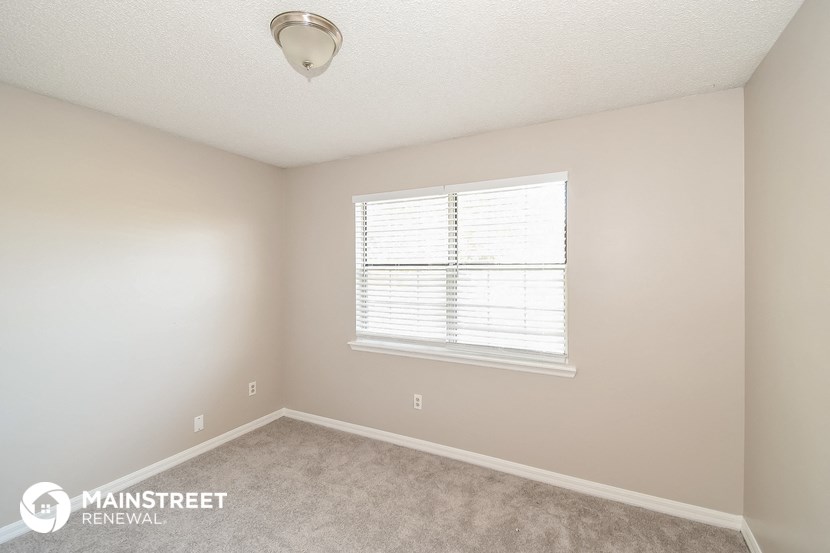 a bedroom with a large window and a carpeted floor