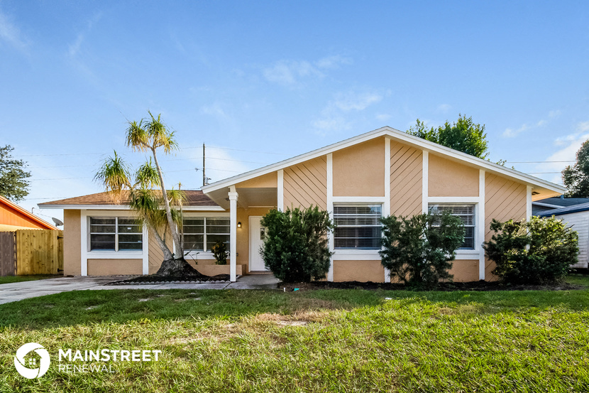 a small tan house with a palm tree in front of it