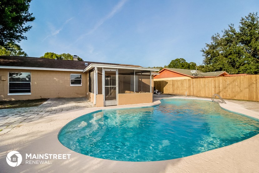 a swimming pool in front of a house with a wooden fence