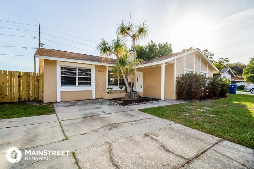 a small beige house with a palm tree in the driveway
