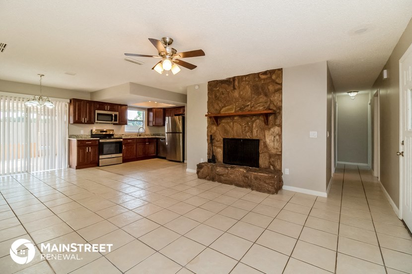 a large living room with a stone fireplace and a kitchen