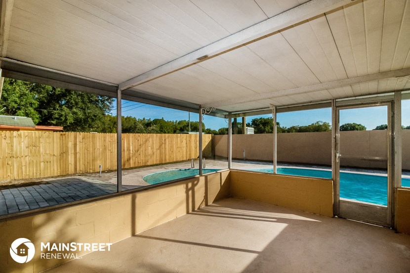 a large covered porch with a pool and a wooden fence