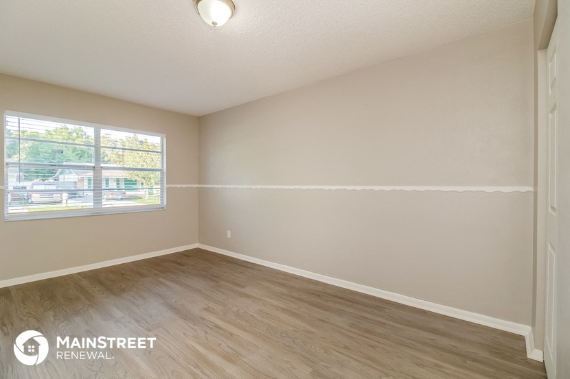 the living room of an empty house with wood flooring and a window