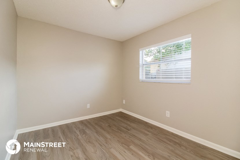 the upstairs bedroom with wood flooring and a window