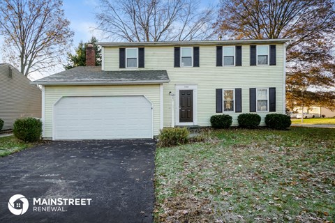 a yellow house with a white garage door and a lawn