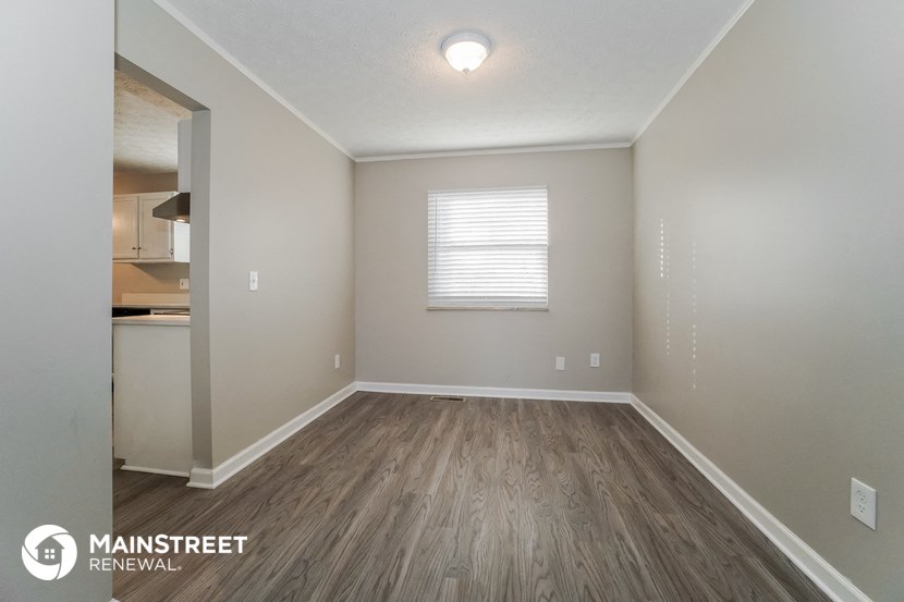 the spacious living room with wood flooring and white walls