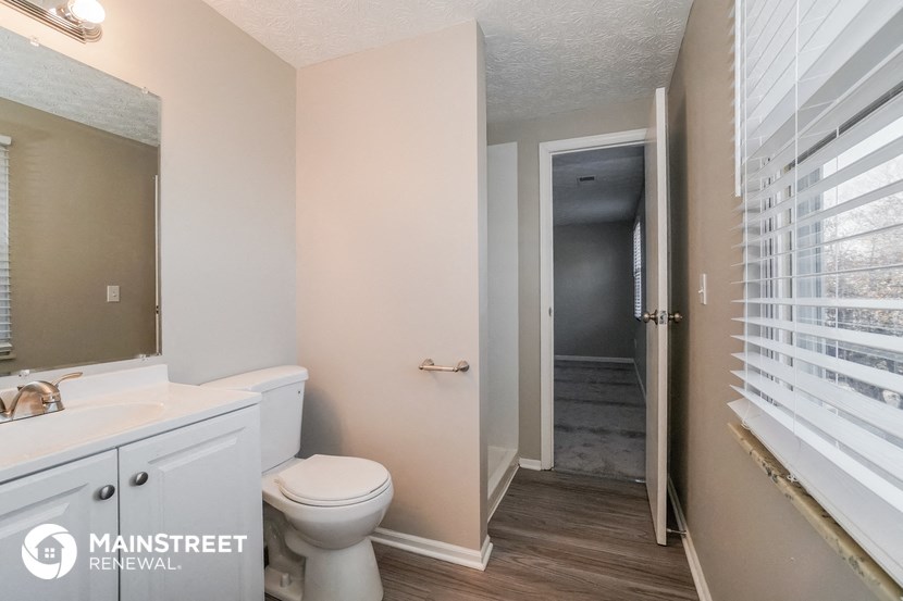 a bathroom with a toilet and a sink and a hall to a closet