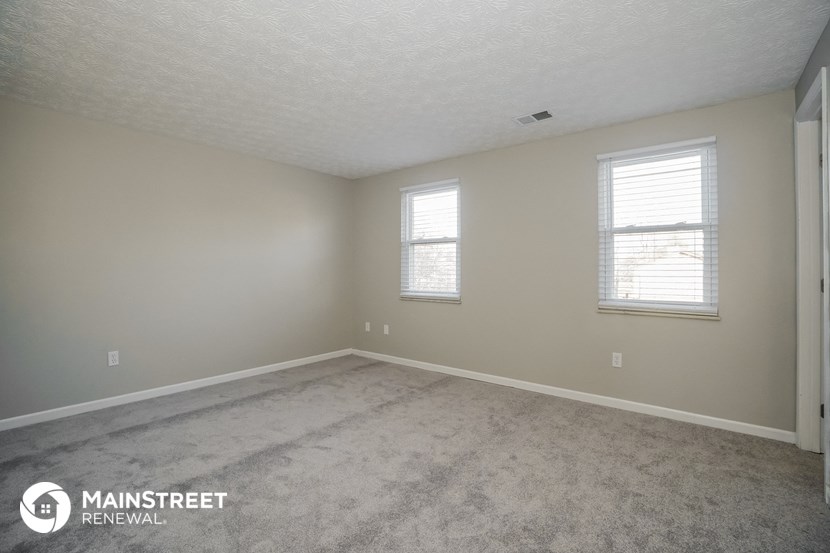 the spacious living room with carpet and two windows