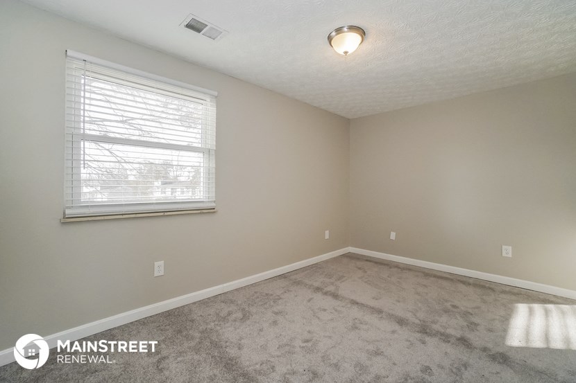 the spacious living room with carpeting and a window