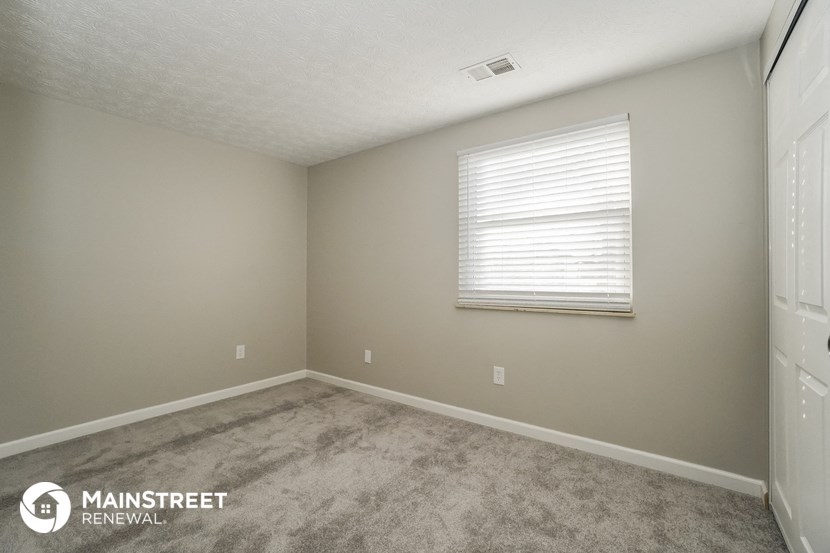 the upstairs bedroom with carpeted flooring and a window