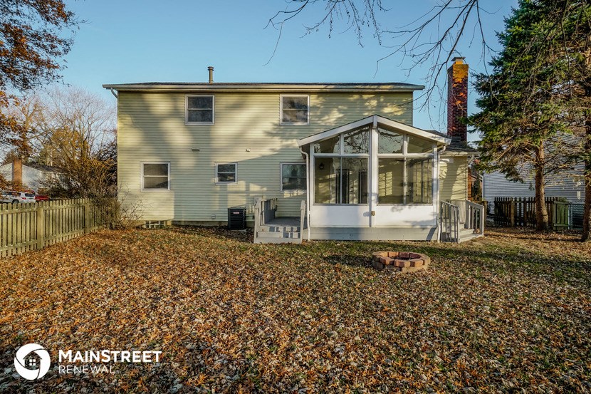 a white house with a porch and a yard with fallen leaves
