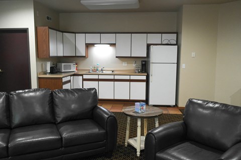 a living room with leather couches in front of a kitchen