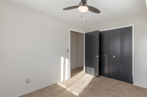 a bedroom with a ceiling fan and a closet