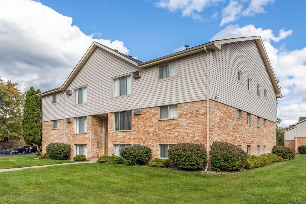 the view of a brick apartment building with green grass