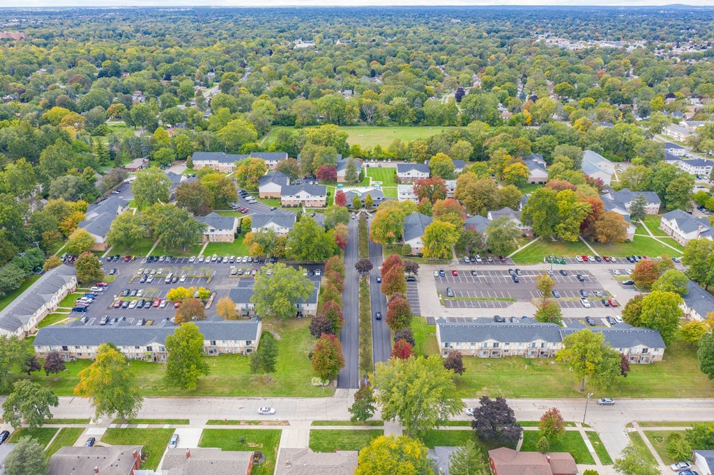 an aerial view of a parking lot with houses and trees