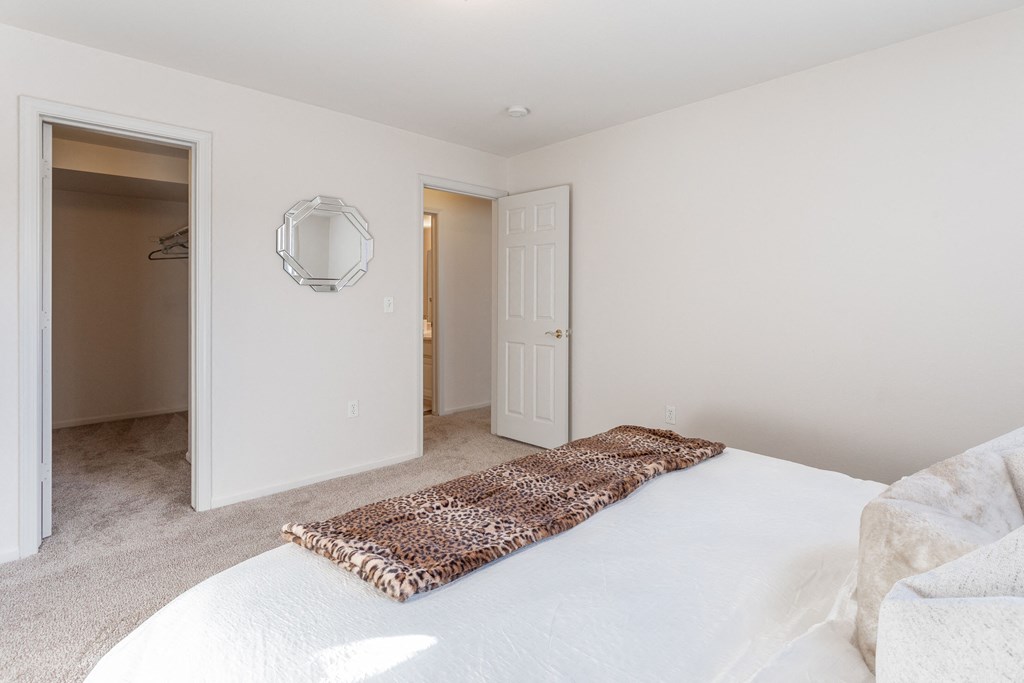 a bedroom with a white bed and a door to a closet