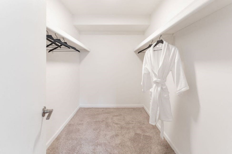 a white walk in closet with a robe hanging on the wall